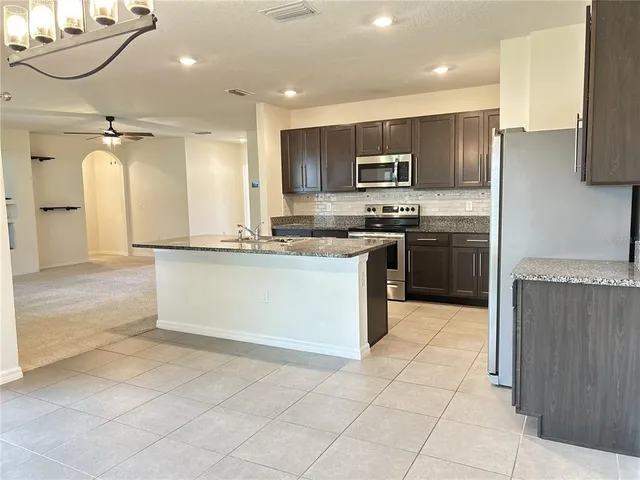 a kitchen with stainless steel appliances granite countertop a refrigerator and a stove top oven