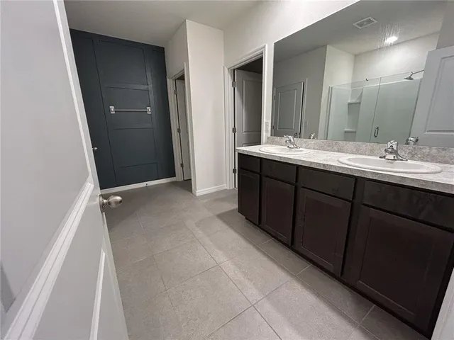 a spacious bathroom with a double vanity sink a mirror and a shower