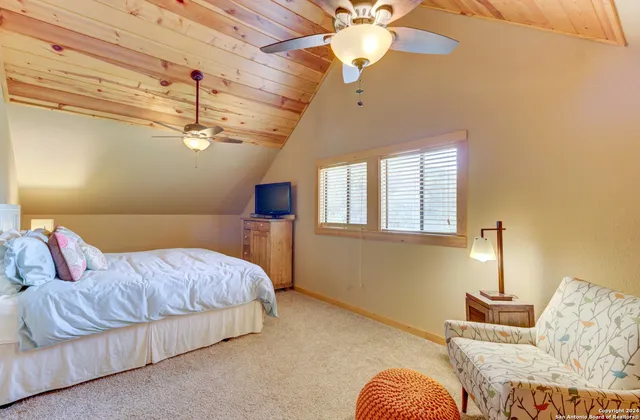 a bedroom with a bed ceiling fan and a wooden floor