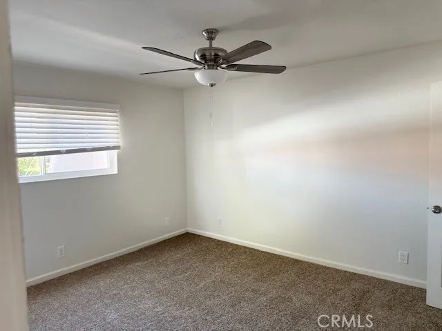 an empty room with a window and a fan