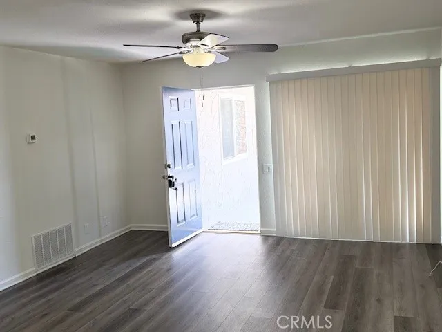 an empty room with wooden floor chandelier fan and windows