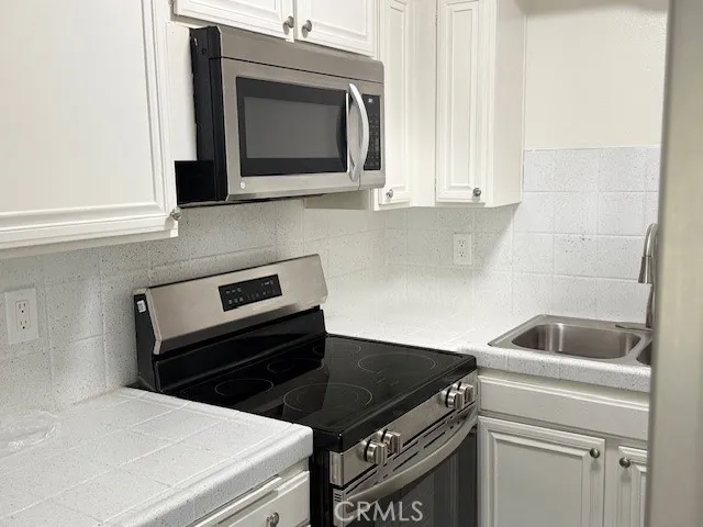 a kitchen with granite countertop white cabinets and black appliances