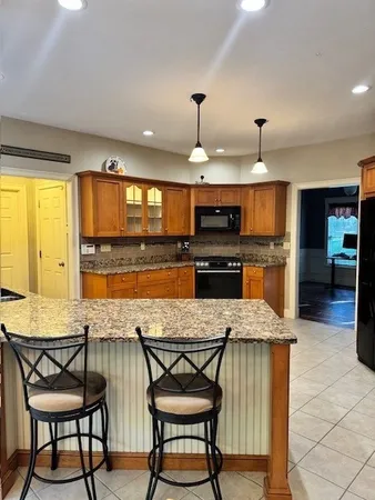 a kitchen with stainless steel appliances granite countertop a stove top oven a sink a dining table and chairs with wooden floor