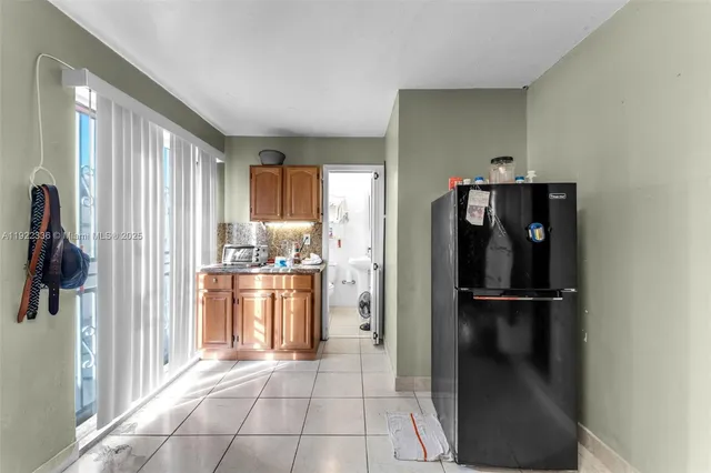a view of a refrigerator in kitchen and a window