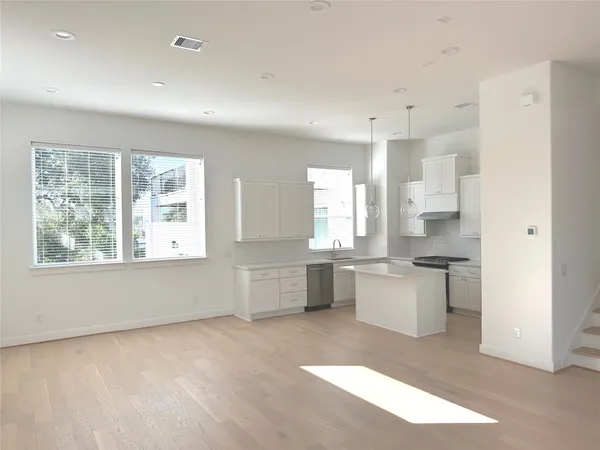 a kitchen with stainless steel appliances granite countertop a stove top oven a sink dishwasher a dining table and chairs with wooden floor