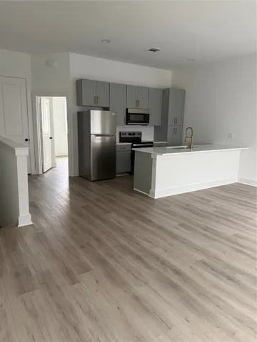 a large kitchen with stainless steel appliances wooden floors and white cabinets