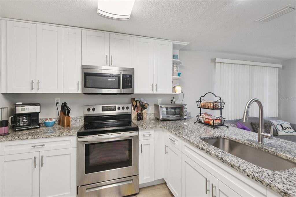 7102 Cherry Laurel Drive Port Richey, FL 34668 - Photo 8 of 39 a kitchen with granite countertop a stove a sink and a microwave