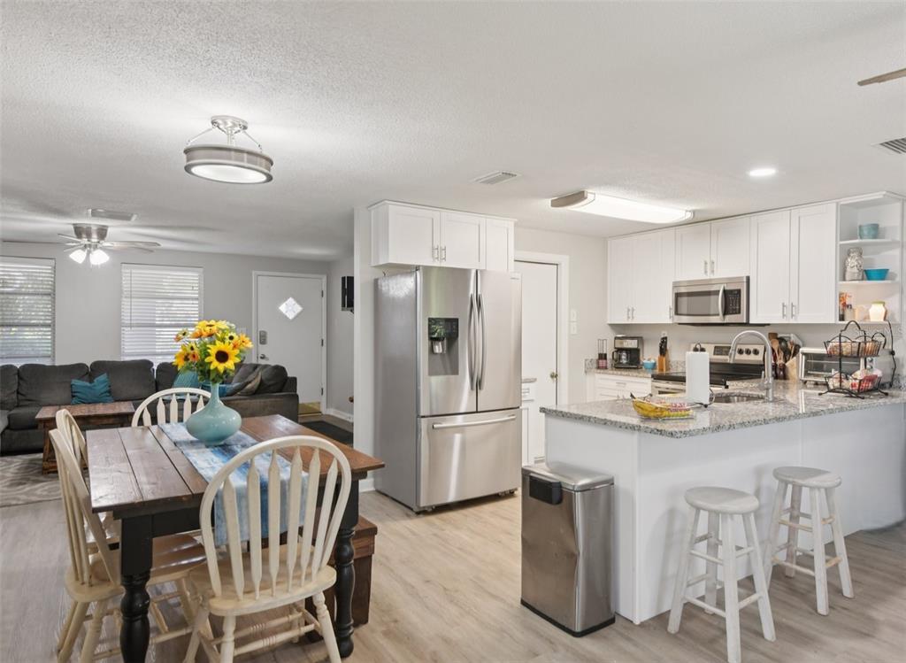 7102 Cherry Laurel Drive Port Richey, FL 34668 - Photo 10 of 39 a kitchen with stainless steel appliances granite countertop a refrigerator a sink dishwasher a dining table and chairs