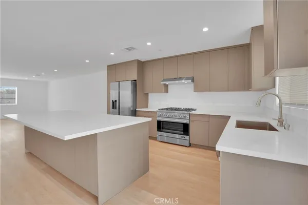 a large kitchen with stainless steel appliances a sink a stove and a refrigerator