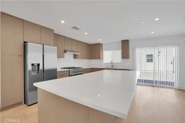 a large kitchen with stainless steel appliances a large counter top a stove and a refrigerator