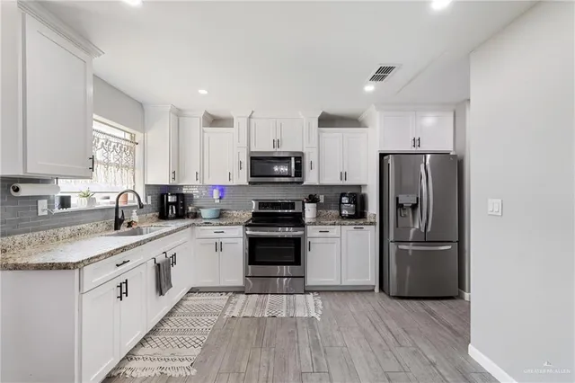 a kitchen with white cabinets stainless steel appliances and a window