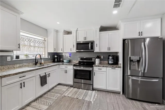 a kitchen with white cabinets and stainless steel appliances
