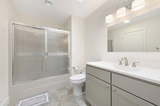 a bathroom with a granite countertop sink toilet and shower