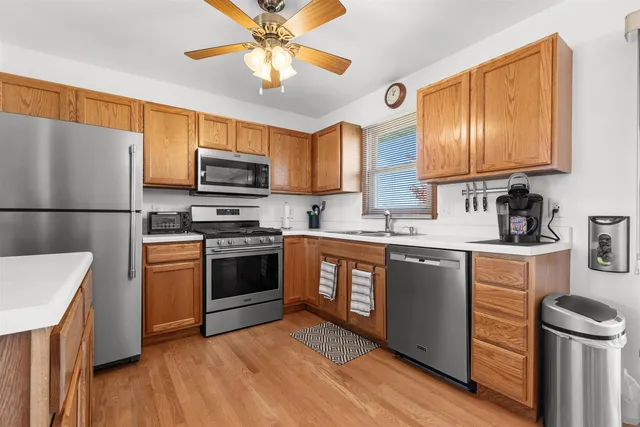 a kitchen with granite countertop a refrigerator a stove top oven a sink and dishwasher with wooden floor