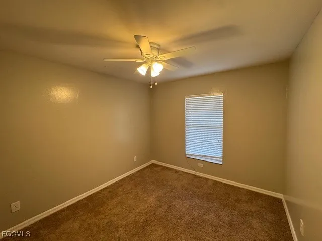 an empty room with a window and ceiling fan