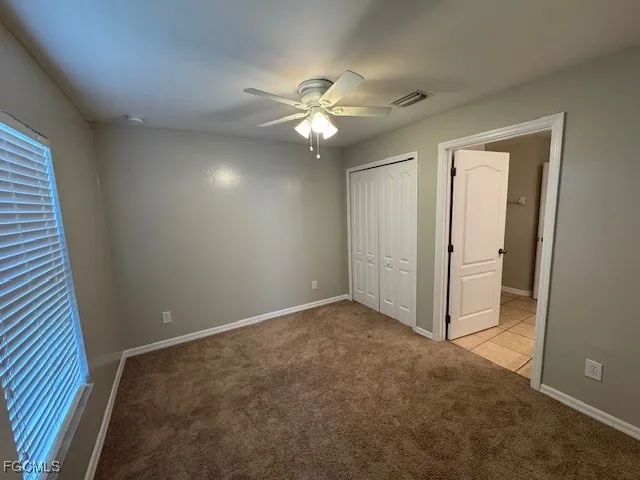 an empty room with closet and a ceiling fan