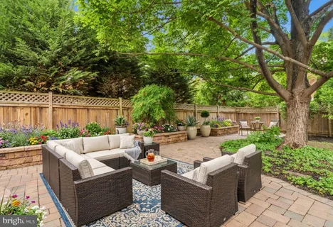 a view of a patio with couches table and chairs potted plants and large tree