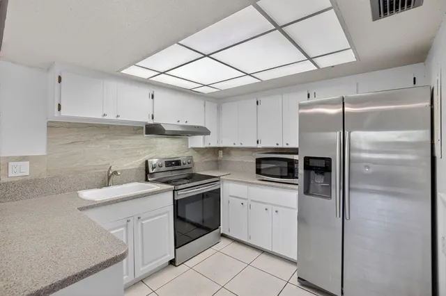 a kitchen with granite countertop white cabinets and stainless steel appliances
