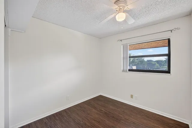 an empty room with wooden floor and a ceiling fan