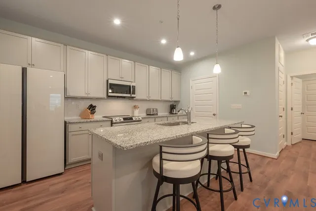 a kitchen with a sink a stove a refrigerator and white cabinets with wooden floor