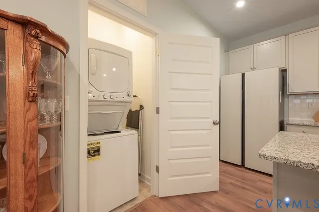 an empty room with wooden floor and way to kitchen