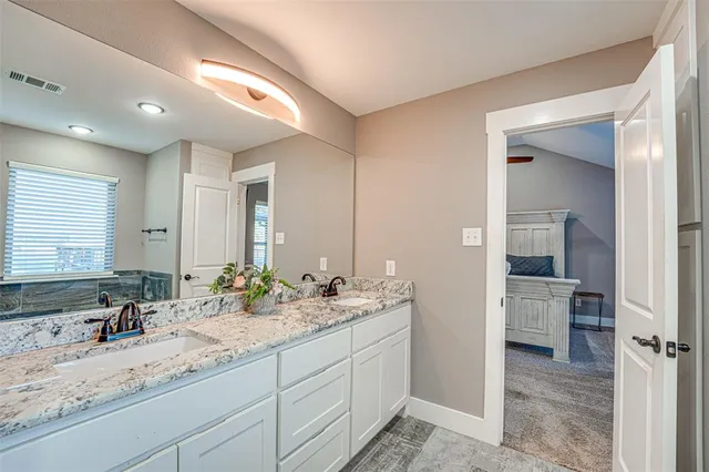 a bathroom with a sink double vanity granite tub shower and a mirror