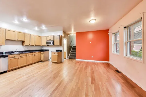a kitchen with stainless steel appliances granite countertop a stove a sink and a refrigerator with wooden floor