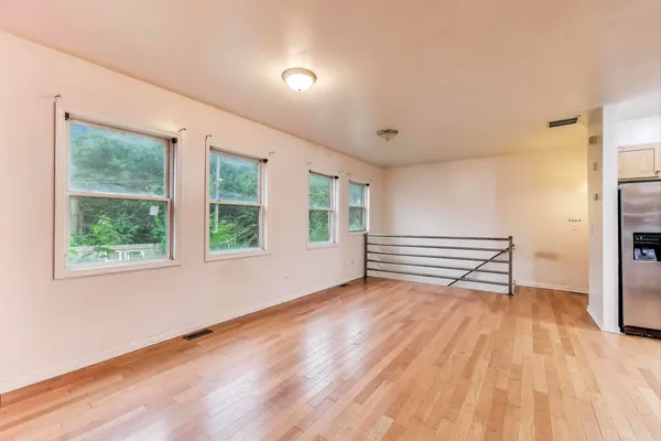 a view of empty room with wooden floor and fan