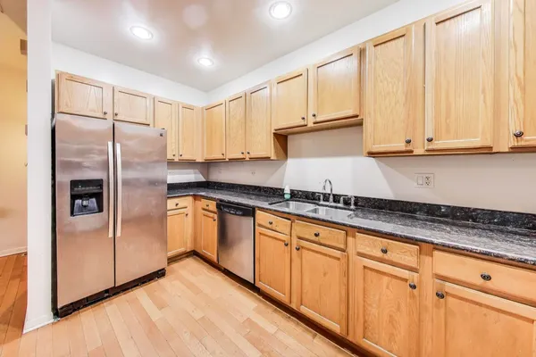 a kitchen with granite countertop a refrigerator sink and cabinets
