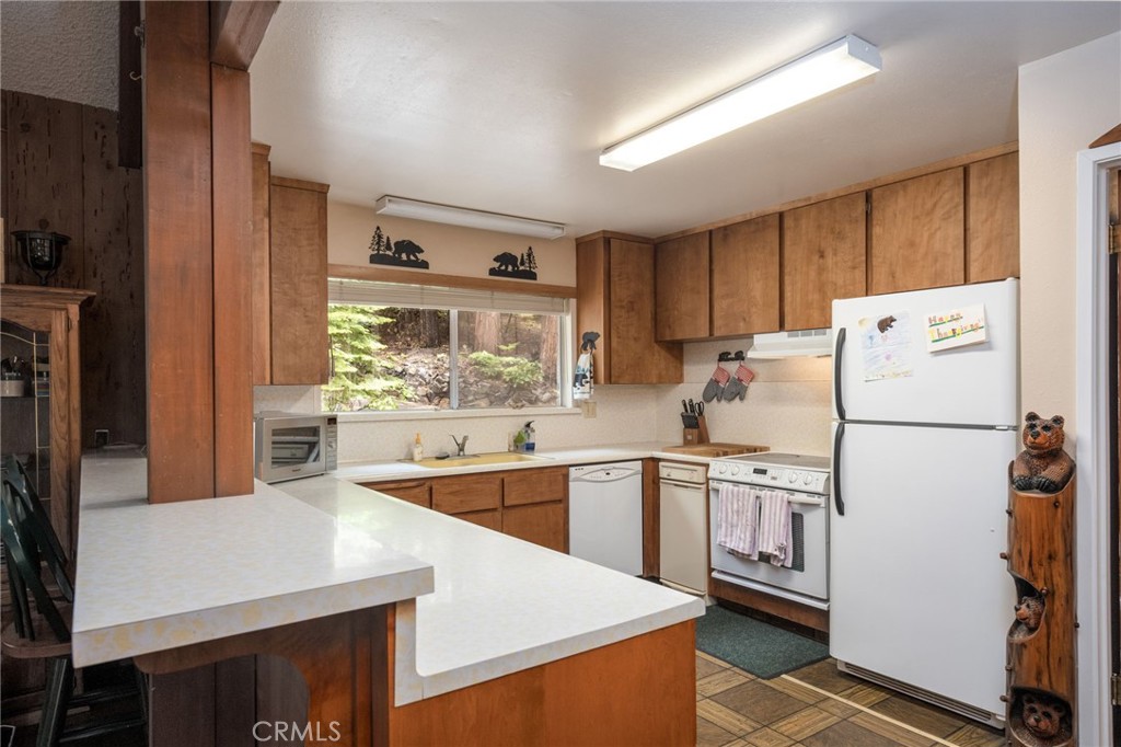 7663 Forest Drive Fish Camp, CA 93623 - Photo 9 of 43 a kitchen with stainless steel appliances a refrigerator a sink and white cabinets