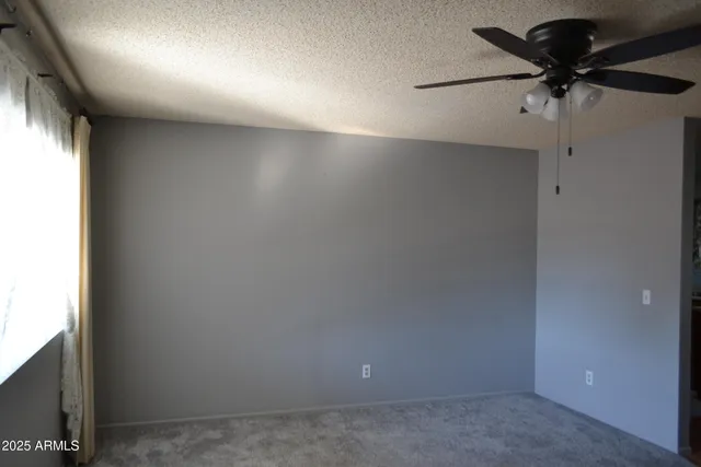 an empty room with a ceiling fan and a window