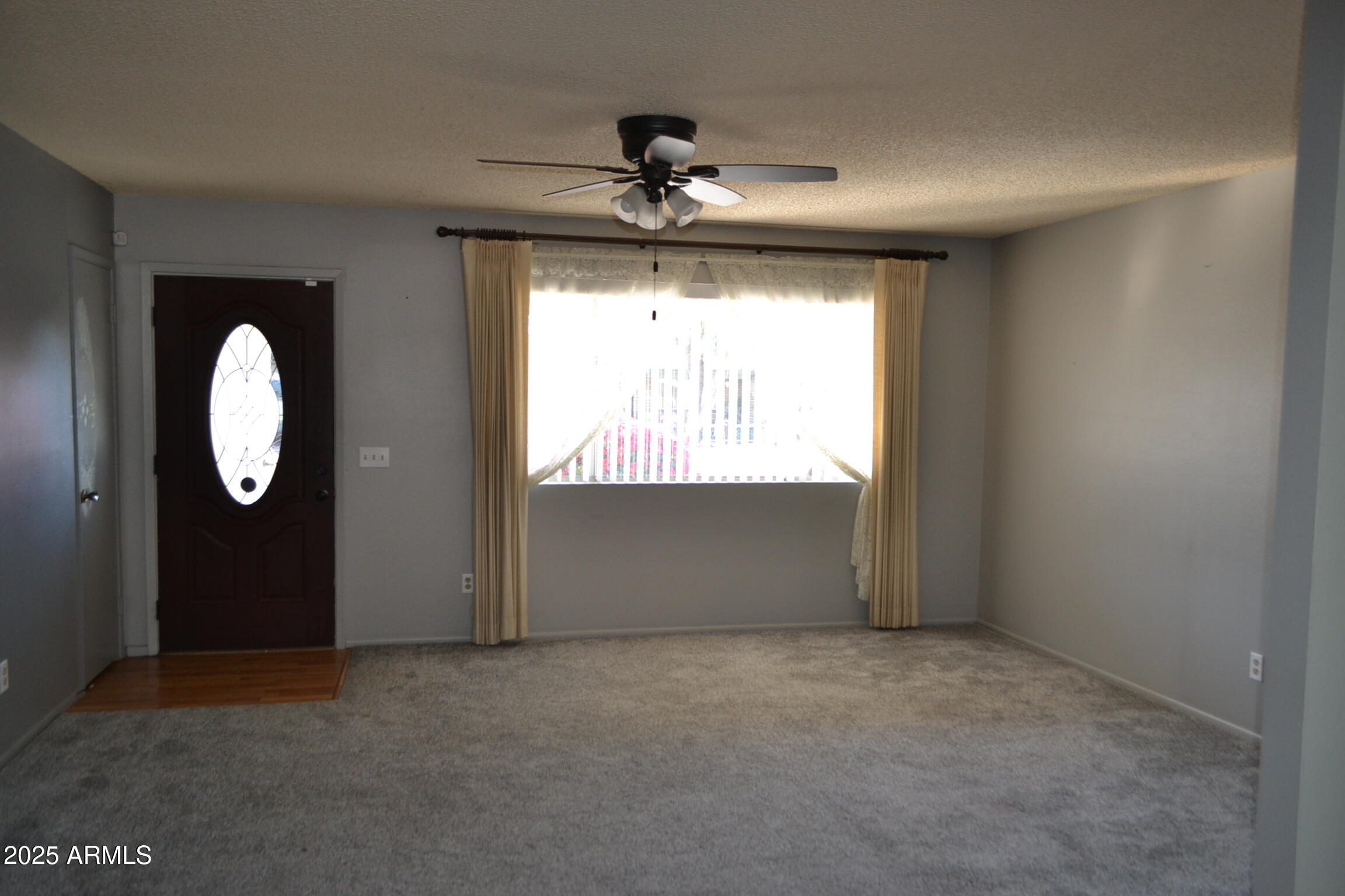 1710 West 13th Avenue Apache Junction, AZ 85120 - Photo 4 of 24 an empty room with windows and fan