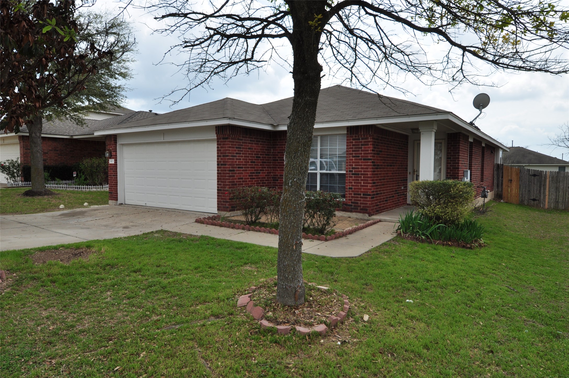 1409 Tea Leaf Drive Pflugerville, TX 78660 - Photo 18 of 18 A well-maintained red brick home features a convenient attached garage and mature landscaping.