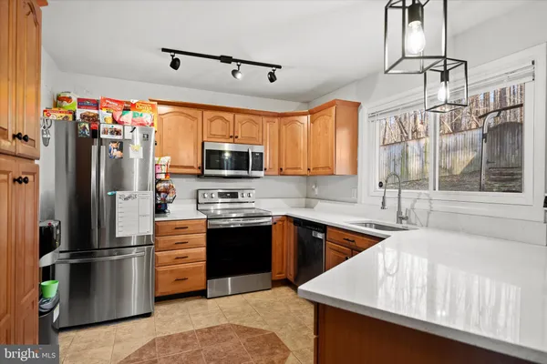 a kitchen with stainless steel appliances granite countertop a refrigerator a sink dishwasher a stove and white cabinets with wooden floor