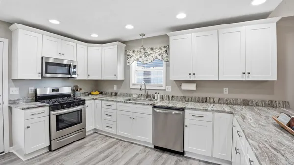 a kitchen with granite countertop white cabinets and white appliances