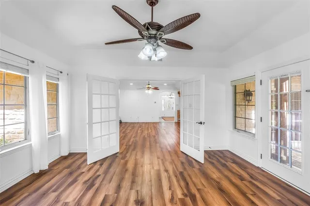 a view of empty room with wooden floor and fan