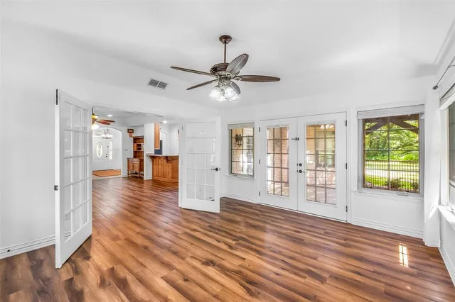 a view of an empty room with wooden floor and a window