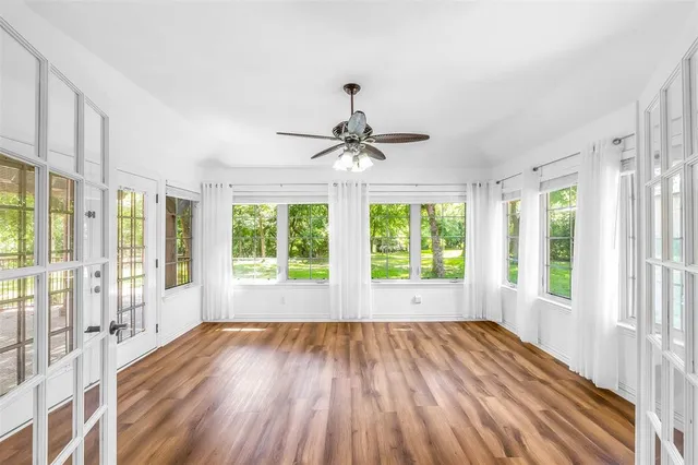 a view of empty room with wooden floor and fan