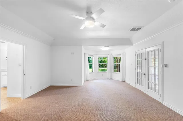 an empty room with windows and chandelier fan