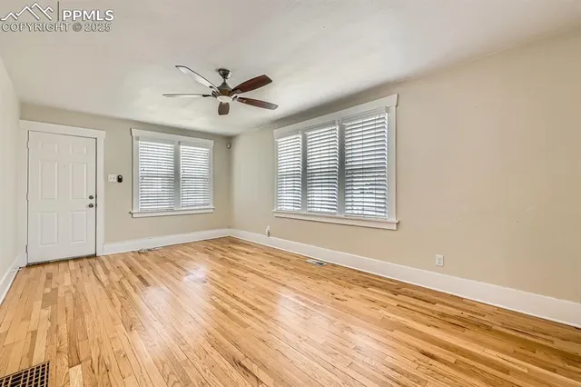 a view of an empty room with wooden floor and a window