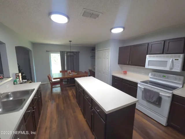 a kitchen with kitchen island a sink appliances and cabinets