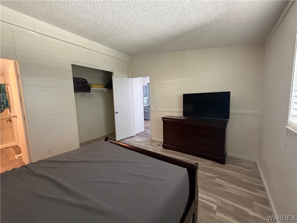 1910 Rio Grande Road Bullhead City, AZ 86442 - Photo 16 of 29 Bedroom featuring wood-finish flooring, white paneling on walls, and an open closet with hanging space
