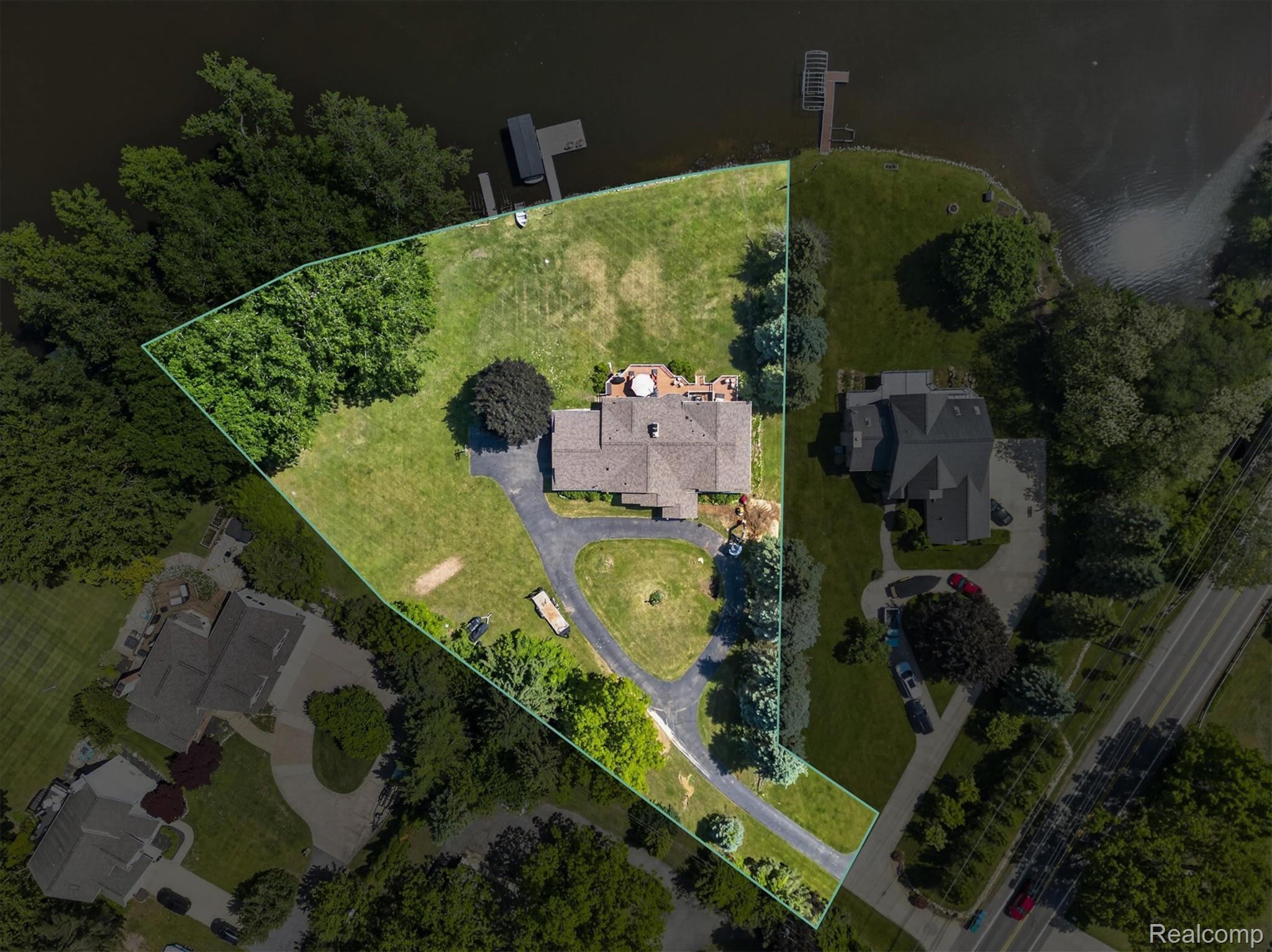 3860 East Commerce Road Commerce Township, MI 48382 - Photo 72 of 72 Expansive waterfront property featuring a private dock, extensive green space, mature trees, a curved driveway, and a spacious rear patio