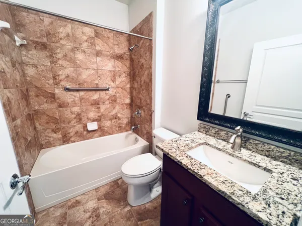 a bathroom with a granite countertop bathtub sink vanity mirror and toilet