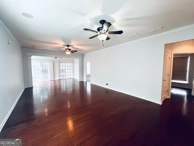 a view of empty room with wooden floor and fan