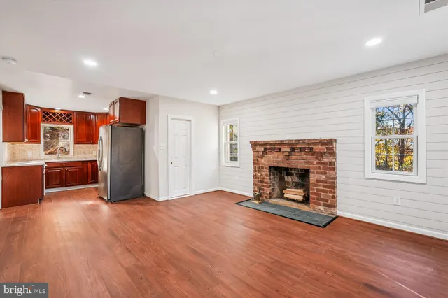 a view of a livingroom with a fireplace wooden floor and a window