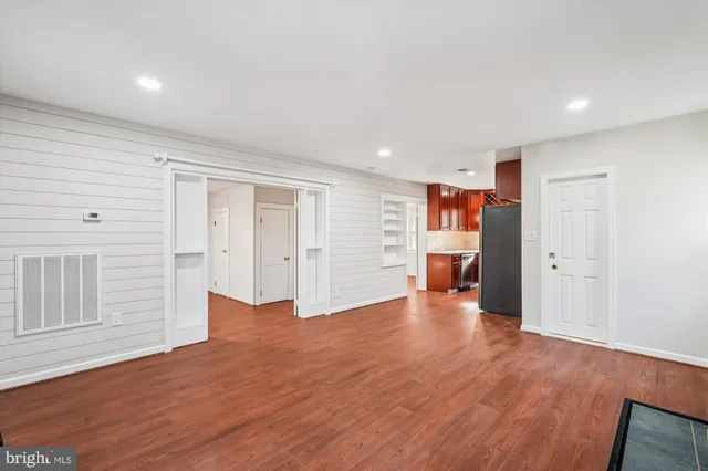 a view of an empty room with wooden floor and closet