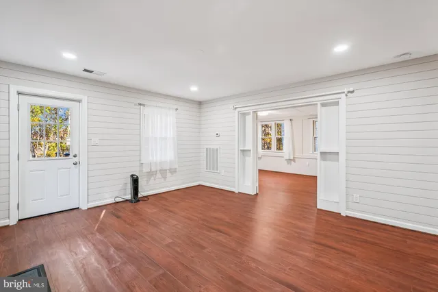 a view of empty room with wooden floor and window
