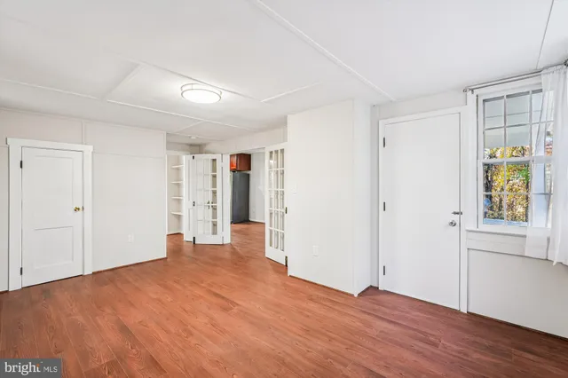 a view of an empty room with window and wooden floor