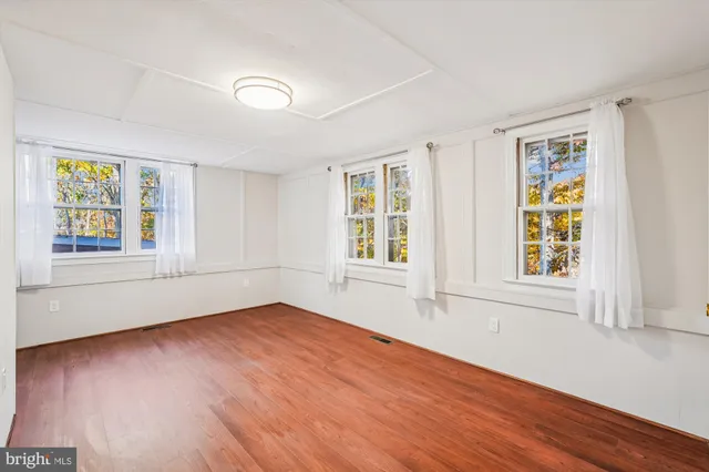 a view of an empty room with wooden floor and window